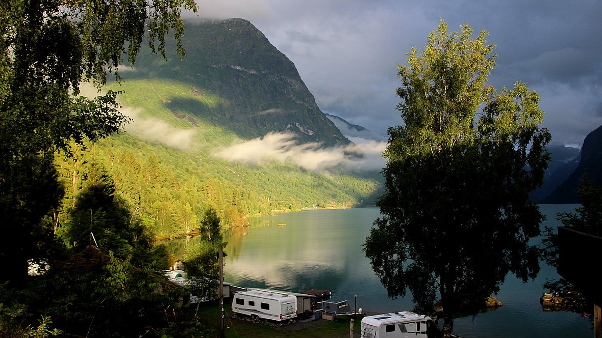 Landschaft mit Bergen und einem See und mehreren Wohnwagen.