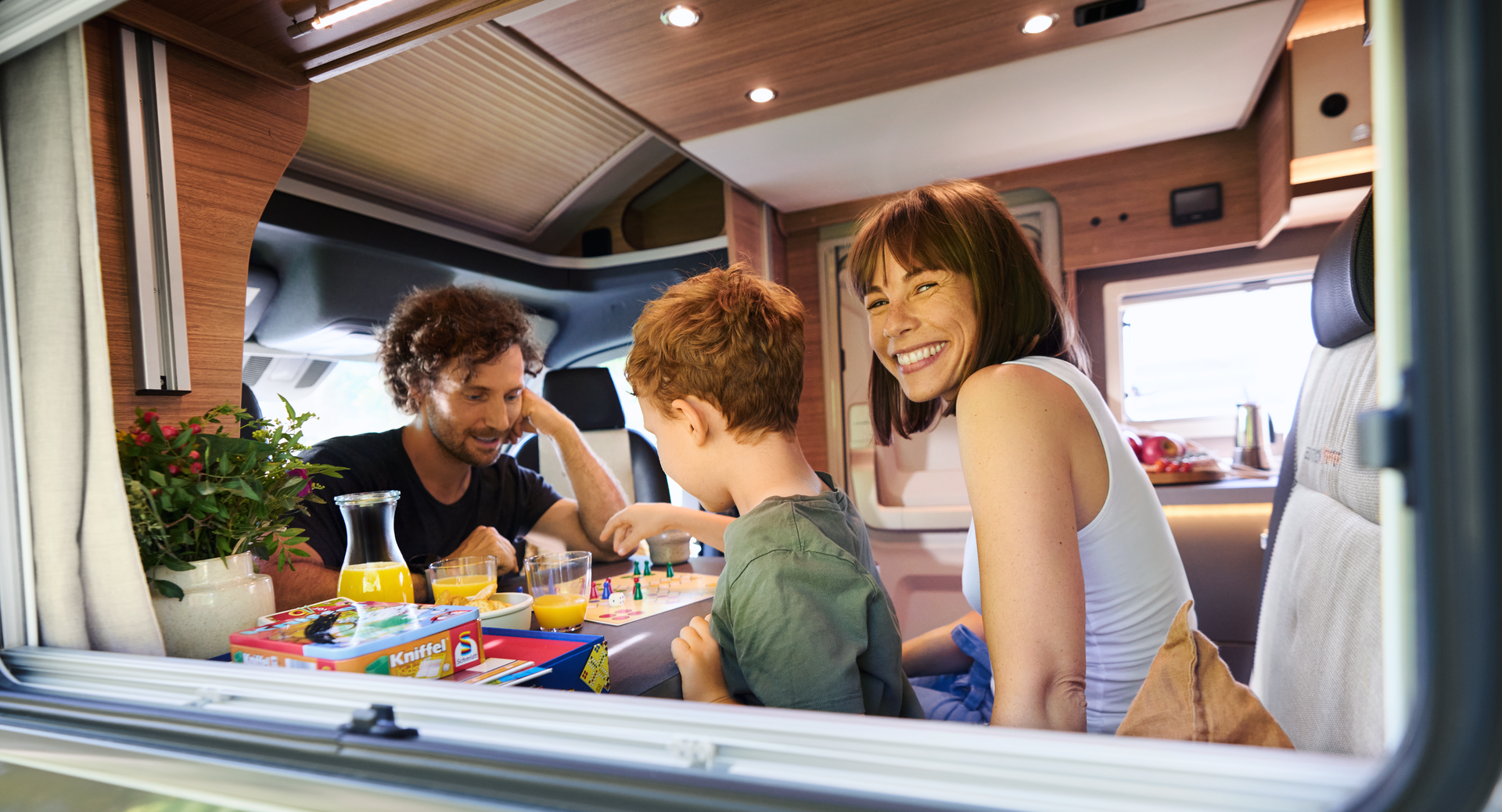 Eine Familie spielt im Wohnmobil an einem Tisch ein Gesellschaftsspiel.