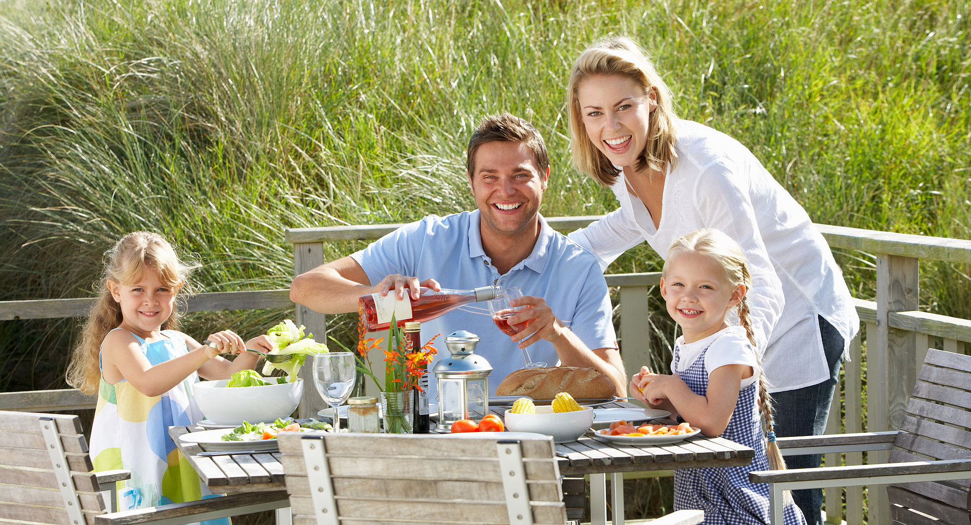 Eine junge Familie genießt den ersten gemeinsamen Camping-Urlaub beim Frühstück.