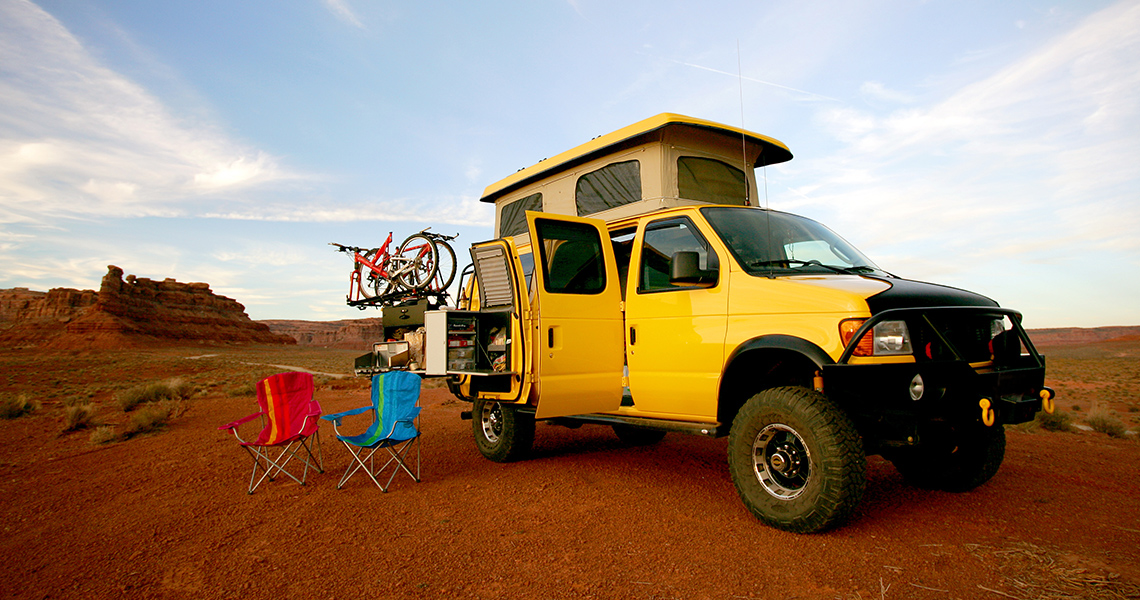 Ein Offroad-Van steht inmitten einer Wüste geparkt.