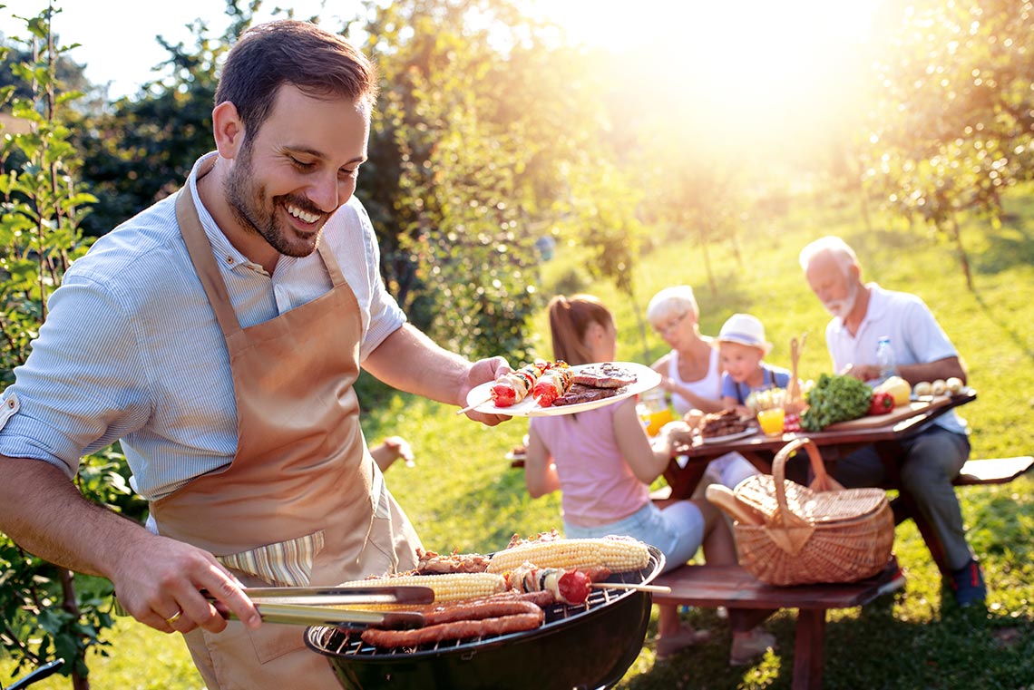 Ein Mann grillt beim Camping für seine Familie.